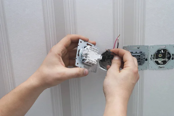 Electrician installs lighting switch — 스톡 사진