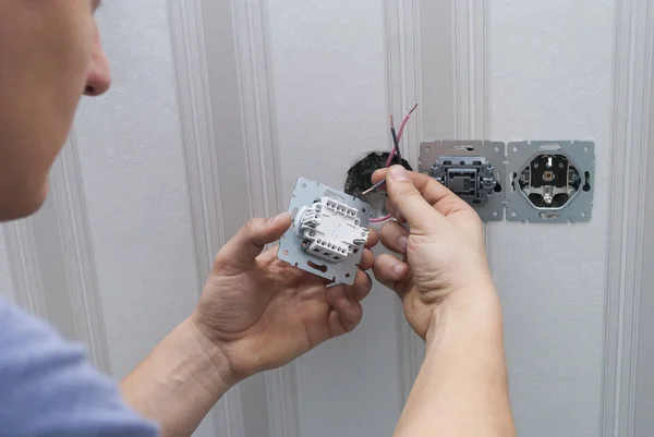 Electrician installs lighting switch — 스톡 사진