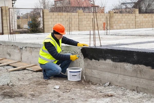 Bauarbeiter Macht Bituminöse Abdichtung Des Fundaments Auf Der Baustelle lizenzfreie Stockbilder