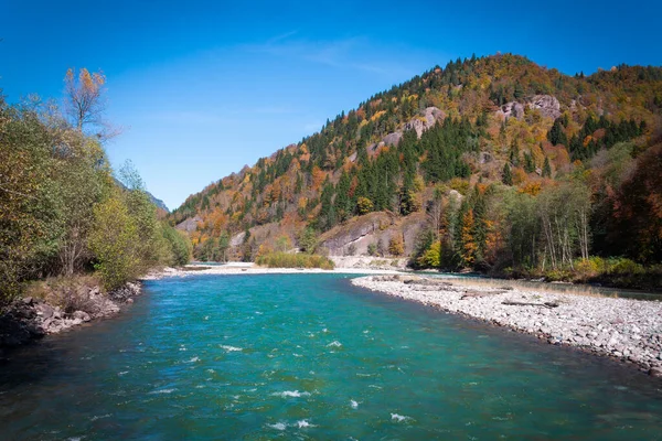 View of the river in the mountains in the middle of autumn trees. Autumn high in the mountains, autumn landscape