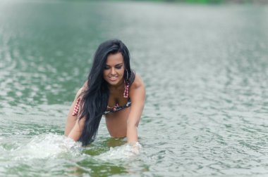 Genç güzel siyah saçlı kadın su sahilde poz