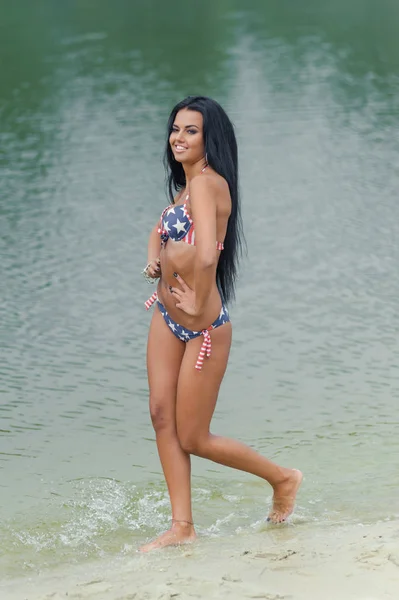 Молода красива чорноволоса жінка позує на пляжі у воді — стокове фото