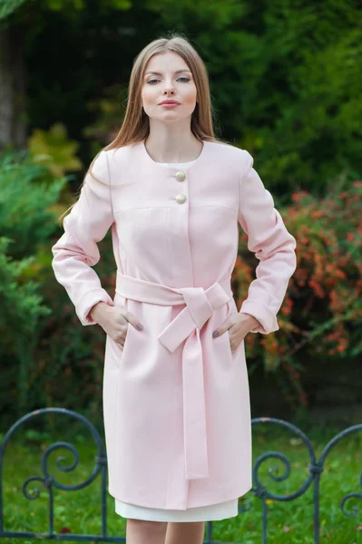 Mooie jonge blonde vrouw roze jas dragen — Stockfoto