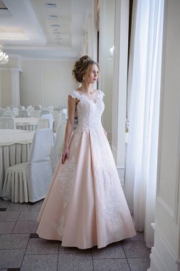 Pencere kenarında gelinlik içinde güzel bir gelin portresi.