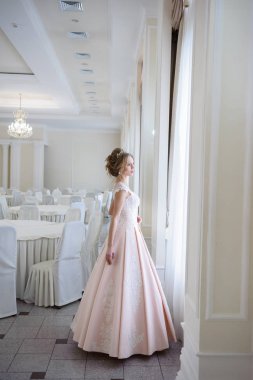 Pencere kenarında gelinlik içinde güzel bir gelin portresi.