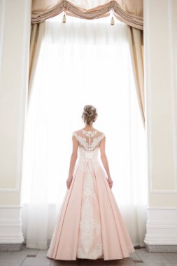 Pencere kenarında gelinlik içinde güzel bir gelin portresi.