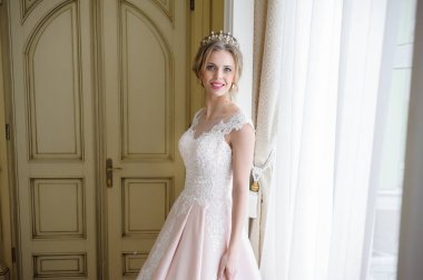 Pencere kenarında gelinlik içinde güzel bir gelin portresi.