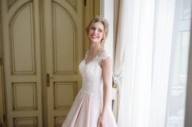 Pencere kenarında gelinlik içinde güzel bir gelin portresi.