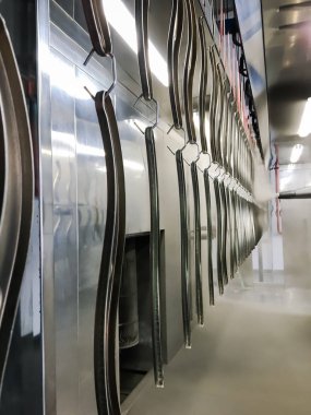 Toz kaplama hattı. Metal paneller, üstteki taşıma hattında askıya alındı. Elektrostatik alanda boyama ürünleri.