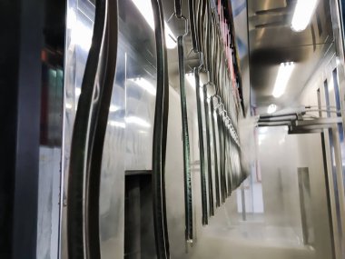 Toz kaplama hattı. Metal paneller, üstteki taşıma hattında askıya alındı. Elektrostatik alanda boyama ürünleri.