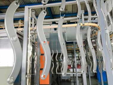Toz kaplama hattı. Metal paneller, üstteki taşıma hattında askıya alındı. Elektrostatik alanda boyama ürünleri.