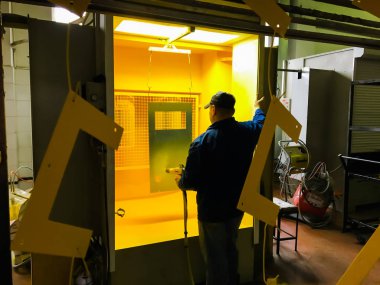 Toz kaplama hattı. Metal paneller, üstteki taşıma hattında askıya alındı. Elektrostatik alanda boyama ürünleri.