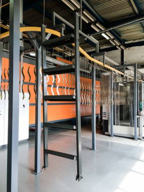 Toz kaplama hattı. Metal paneller, üstteki taşıma hattında askıya alındı. Elektrostatik alanda boyama ürünleri.