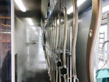 Toz kaplama hattı. Metal paneller, üstteki taşıma hattında askıya alındı. Elektrostatik alanda boyama ürünleri.