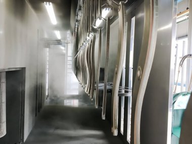 Toz kaplama hattı. Metal paneller, üstteki taşıma hattında askıya alındı. Elektrostatik alanda boyama ürünleri.