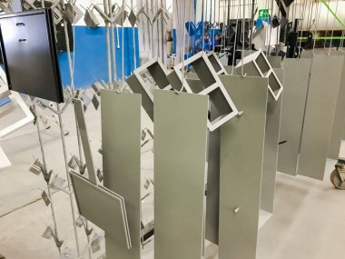 Toz kaplama hattı. Metal paneller, üstteki taşıma hattında askıya alındı. Elektrostatik alanda boyama ürünleri.