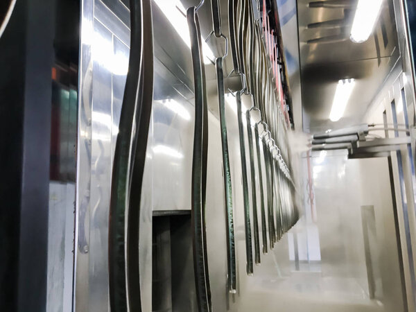 Линия порошкового покрытия. Металлические панели подвешиваются на воздушной конвейерной линии. Живопись в электростатическом поле.