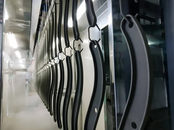 Toz kaplama hattı. Metal paneller, üstteki taşıma hattında askıya alındı. Elektrostatik alanda boyama ürünleri.
