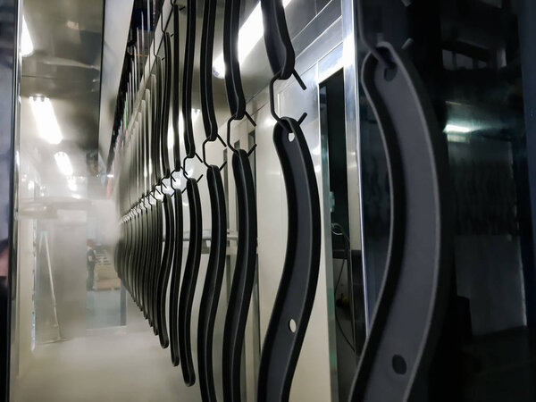 Линия порошкового покрытия. Металлические панели подвешиваются на воздушной конвейерной линии. Живопись в электростатическом поле.