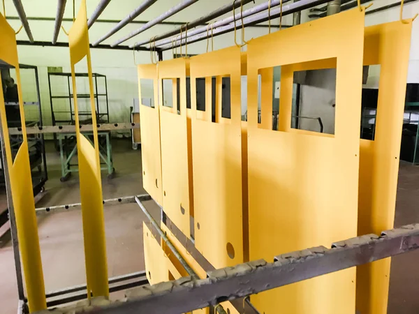 Powder coating line. Metal panels are suspended on an overhead conveyor line. Painting products in an electrostatic field.