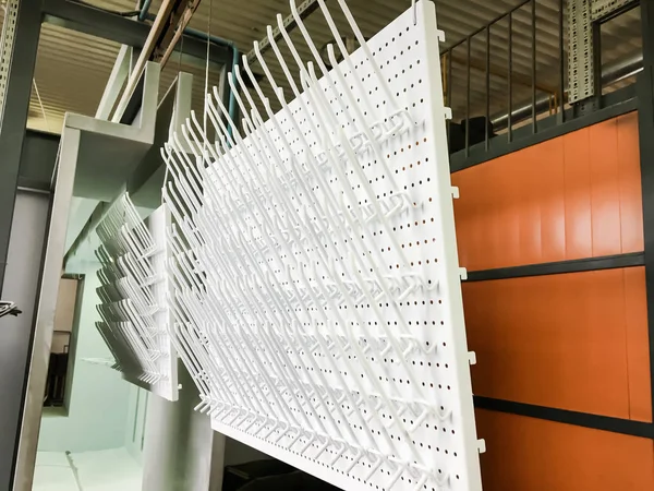 Powder coating line. Metal panels are suspended on an overhead conveyor line. Painting products in an electrostatic field.