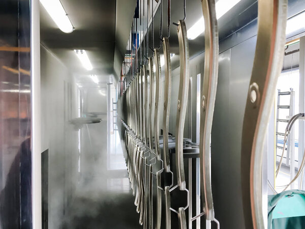 Линия порошкового покрытия. Металлические панели подвешиваются на воздушной конвейерной линии. Живопись в электростатическом поле.