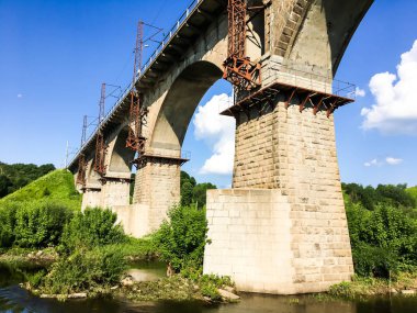 Güneşli bir günde nehirden geçen taş köprü