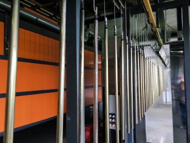 Toz kaplama hattı. Metal paneller, üstteki taşıma hattında askıya alındı. Elektrostatik alanda boyama ürünleri.