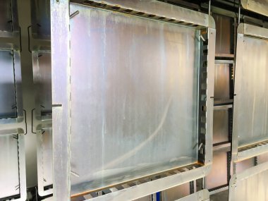 Toz kaplama hattı. Metal paneller, üstteki taşıma hattında askıya alındı. Elektrostatik alanda boyama ürünleri.