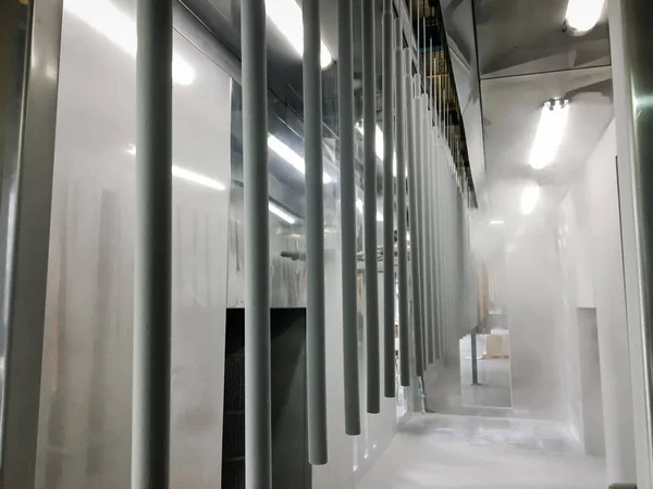 Toz kaplama hattı. Metal paneller, üstteki taşıma hattında askıya alındı. Elektrostatik alanda boyama ürünleri.