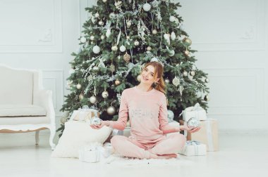 Mutlu genç bir kadın Noel tatilinde güzel bir Noel ağacının yanında hediyelerle