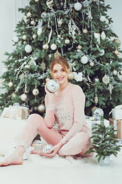 Mutlu genç bir kadın Noel tatilinde güzel bir Noel ağacının yanında hediyelerle