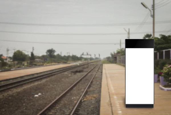 Cartelera en blanco en una estación de tren junto a las vías del tren borrosa —  Fotos de Stock