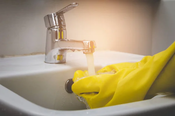 Hand of water tap housemaid wearing yellow glove cleaning — Stock Photo, Image