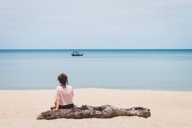 Ahşap oturma ve balıkçı teknesi se bakarak bir kadın