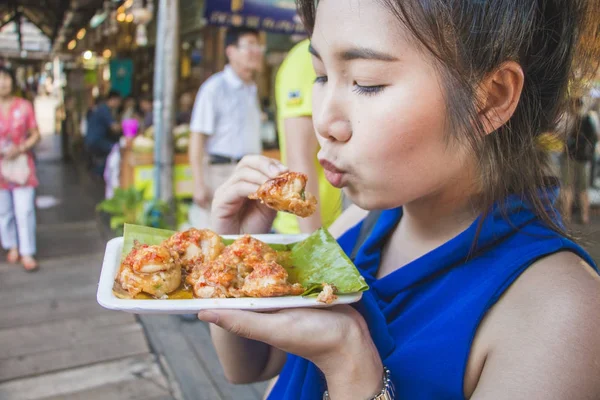 Linda chica de asiático soplando para comer mini frito mejillones en floatin — Foto de Stock