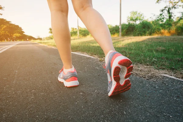 Jovencita corriendo por la carretera de cerca en zapato., al atardecer — Foto de Stock