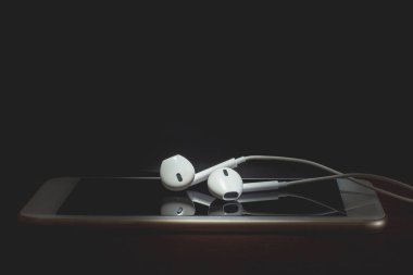 Ahşap masada kulaklık lar ve akıllı telefon