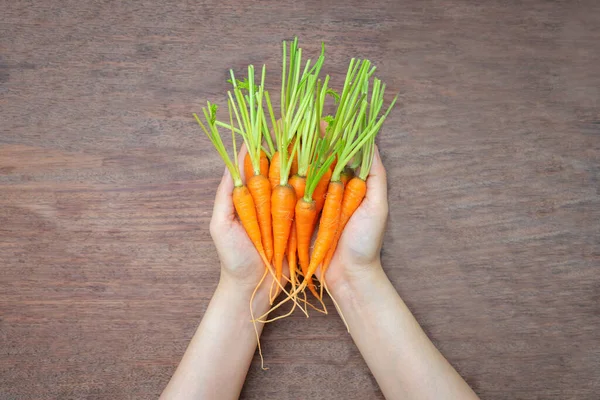 Mano Sosteniendo Zanahorias Frescas Sobre Fondo Madera —  Fotos de Stock