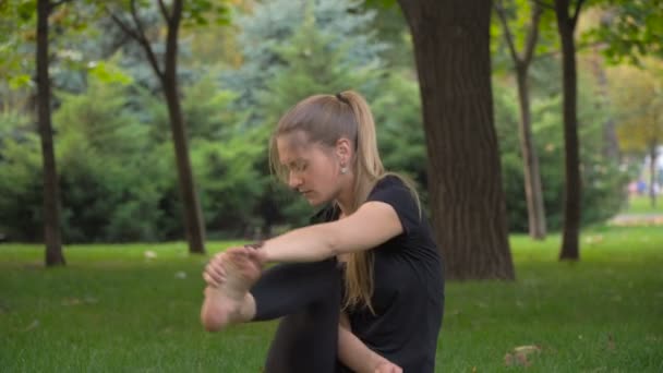 Mladá dívka dělá jógu sedět na trávě — Stock video