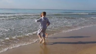 Sahilde bir dalga ile oynayan çocuklar