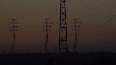 Yüksek voltajlı bir hattın arkaplanında gün doğumu