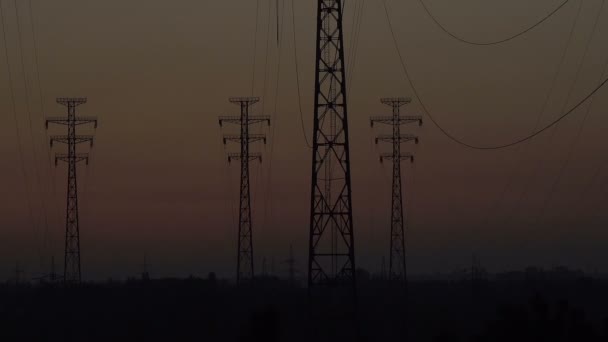 Yüksek voltajlı bir hattın arkaplanında gün doğumu — Stok video