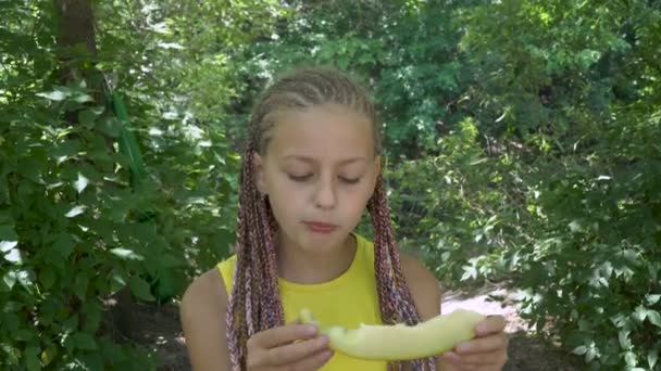 Девушка ест желтую дыню — стоковое видео