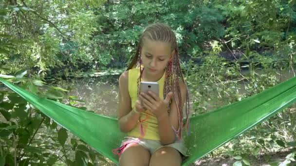 Flicka spela tablett i hängmatta — Stockvideo