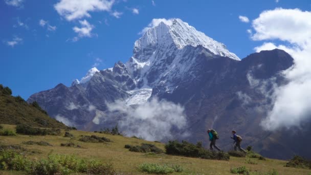 Mädchen mit Rucksäcken erklimmen Berghang im Himalaya — Stockvideo