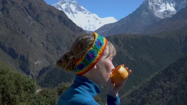 Een meisje is het drinken van thee in de bergen — Stockvideo