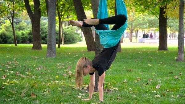 Girl in a park engaged in aerial yoga
