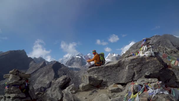 A guy with a map sits on a rock — Stock Video