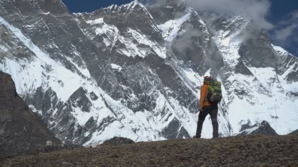 Человек с рюкзаком поднимается на склон горы в Гималаях — стоковое видео